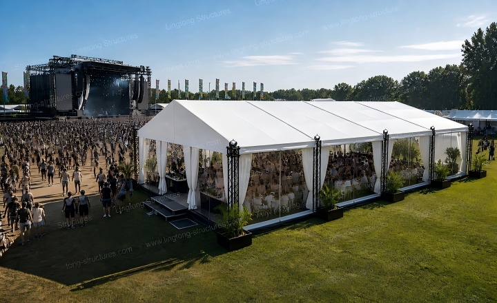 Music festival stage covered by large span marquee tent with VIP lounge area